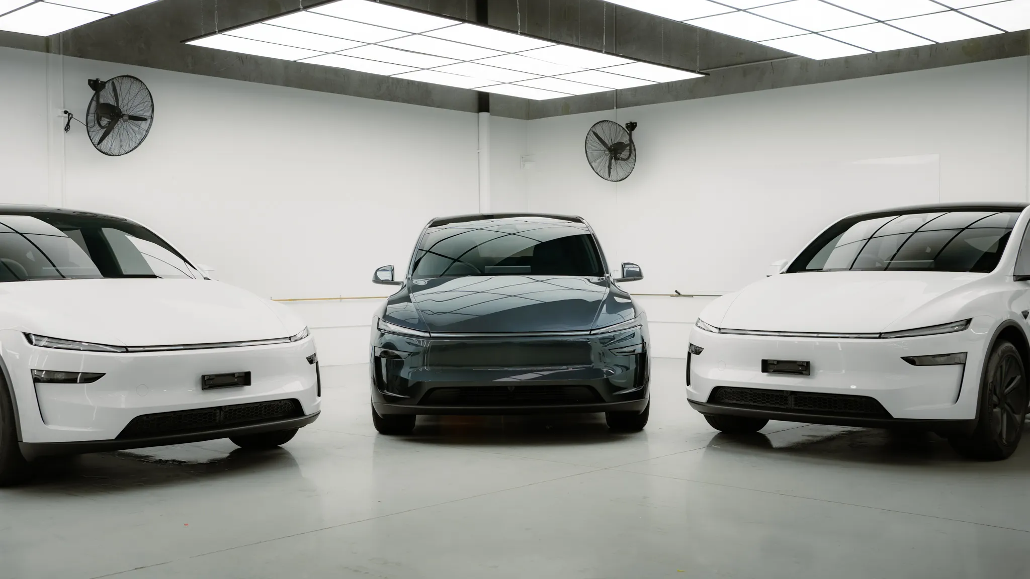 Three Tesla Model Ys under the hex lights at the Deluxe Detail studio