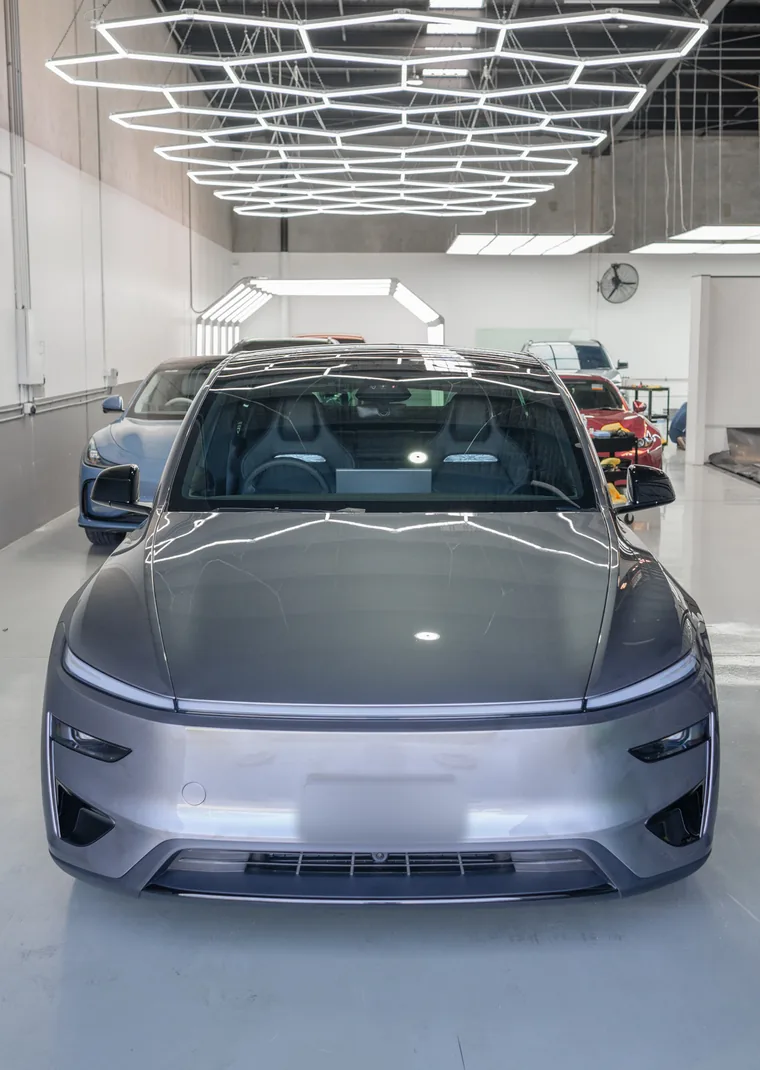 Quicksilver Tesla Model Y under the hex lights at the Deluxe Detail studio