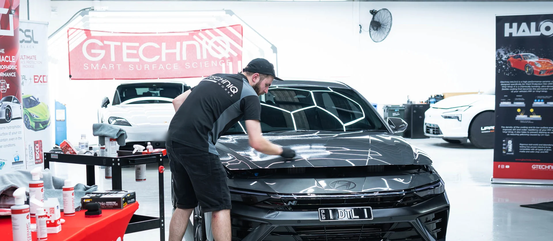 A Gtechniq applicator levelling Crystal Serum Ultra across the bonnet of a black car in the Deluxe Detail studio