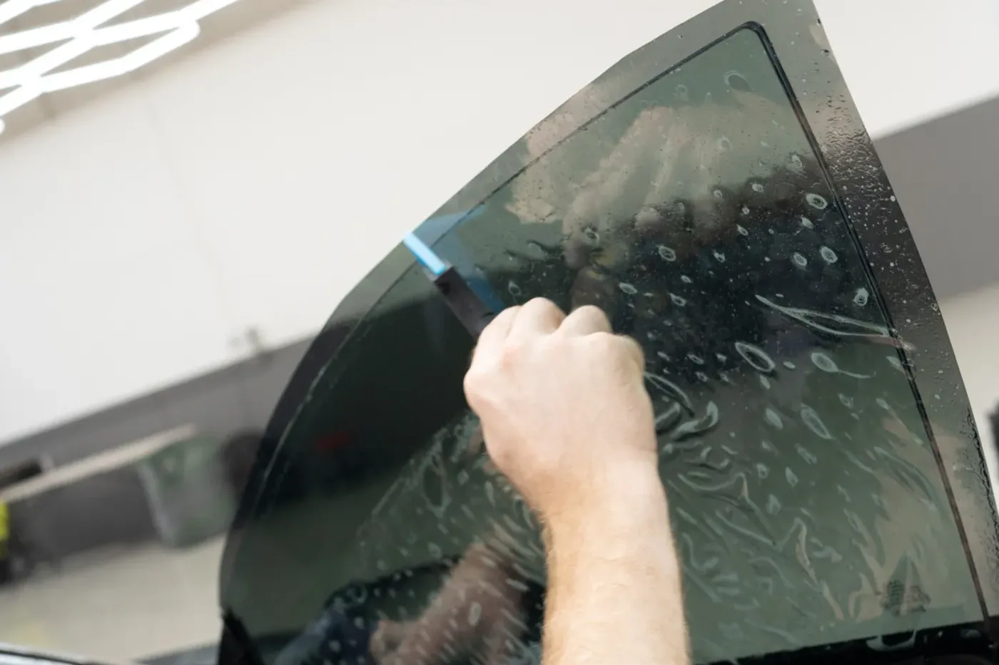 Installer squeegeeing window film onto a front side window