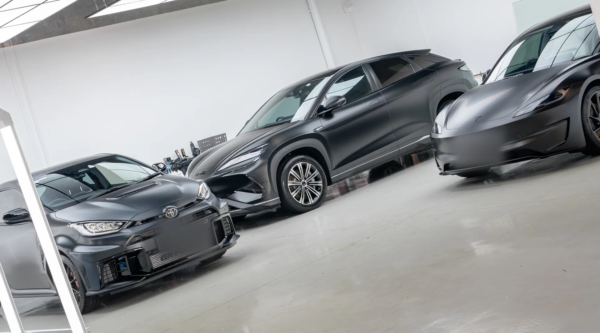 Three satin PPF wrapped cars in the Deluxe Detail studio bays